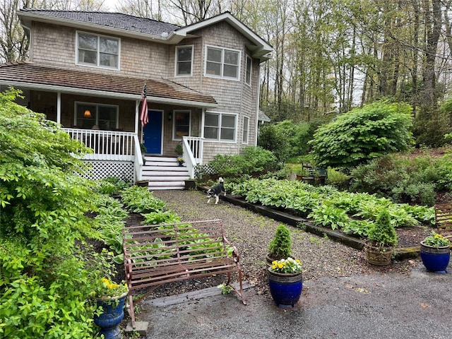 view of front of house featuring covered porch and a shingled roof