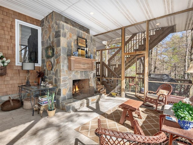 living room featuring a stone fireplace, stairway, and wood finished floors