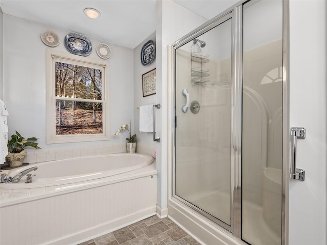 full bathroom featuring a garden tub, stone finish flooring, and a shower stall