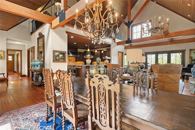 dining area with a chandelier, high vaulted ceiling, hardwood / wood-style flooring, beam ceiling, and baseboards