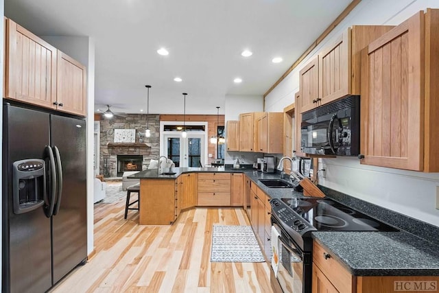 kitchen featuring sink, a kitchen breakfast bar, decorative light fixtures, black appliances, and light brown cabinets