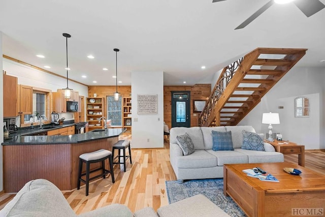 living room featuring ceiling fan, sink, and light hardwood / wood-style floors