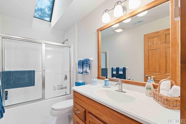 full bathroom featuring combined bath / shower with glass door, vanity, toilet, and a skylight