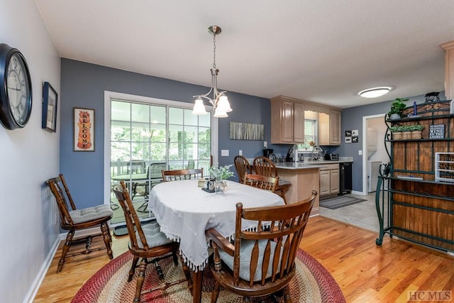 dining area featuring sink, light hardwood / wood-style flooring, and a notable chandelier