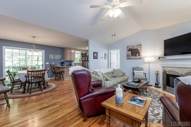 living room featuring ceiling fan, lofted ceiling, and light wood-type flooring