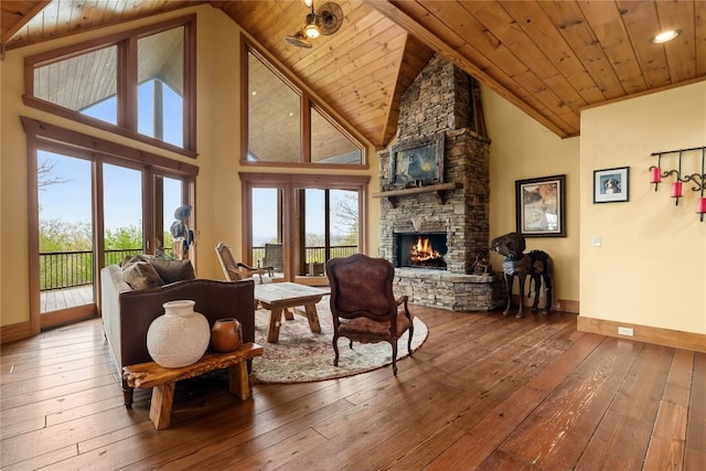 living area with a stone fireplace, hardwood / wood-style floors, wood ceiling, baseboards, and plenty of natural light