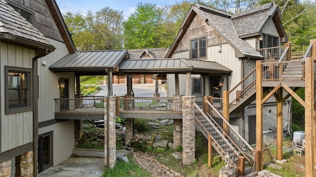 back of property featuring stairs, a standing seam roof, and metal roof