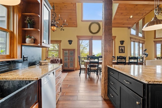 kitchen with dishwasher, a towering ceiling, dark cabinetry, open shelves, and light stone countertops