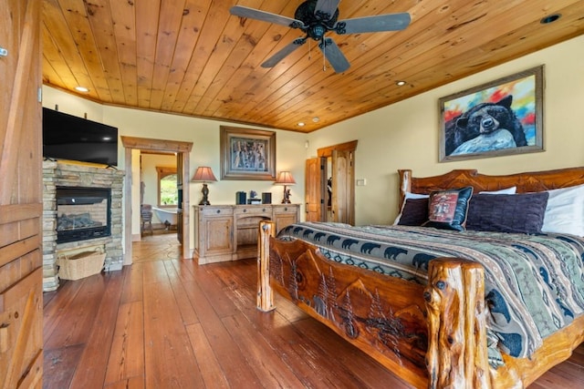 bedroom with hardwood / wood-style flooring, a stone fireplace, wood ceiling, and recessed lighting