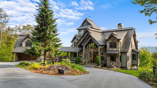 tudor house with a standing seam roof, stone siding, and a chimney