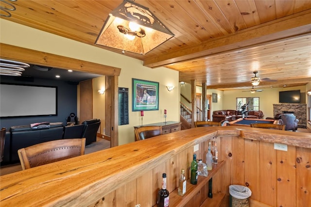 dining area with wooden ceiling, a dry bar, stairway, a ceiling fan, and a stone fireplace
