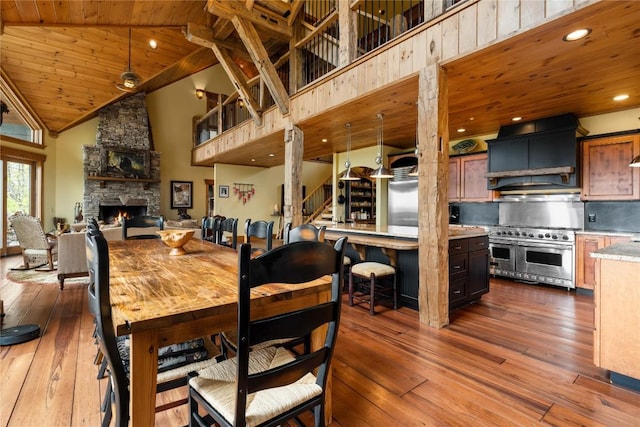 dining space featuring wooden ceiling, dark wood-style floors, high vaulted ceiling, a fireplace, and recessed lighting