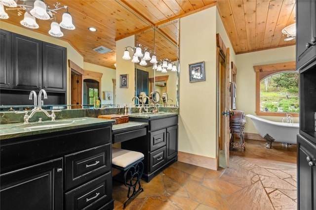 bathroom featuring wood ceiling, a chandelier, stone tile floors, double vanity, and a freestanding tub