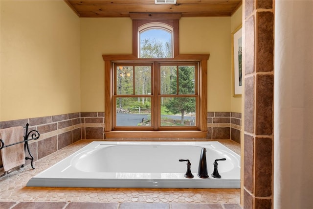 bathroom featuring wood ceiling and a bath