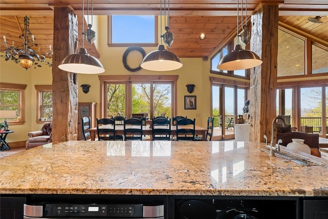 kitchen with high vaulted ceiling, open floor plan, a sink, an island with sink, and light stone countertops