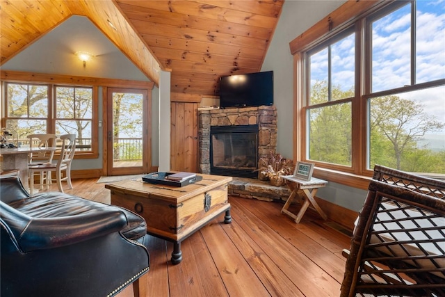 living area featuring lofted ceiling, baseboards, a fireplace, hardwood / wood-style floors, and plenty of natural light