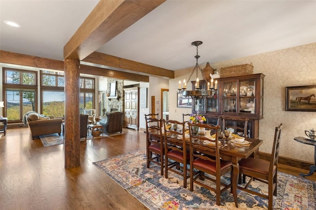 dining space featuring beam ceiling, a chandelier, wood finished floors, baseboards, and wallpapered walls