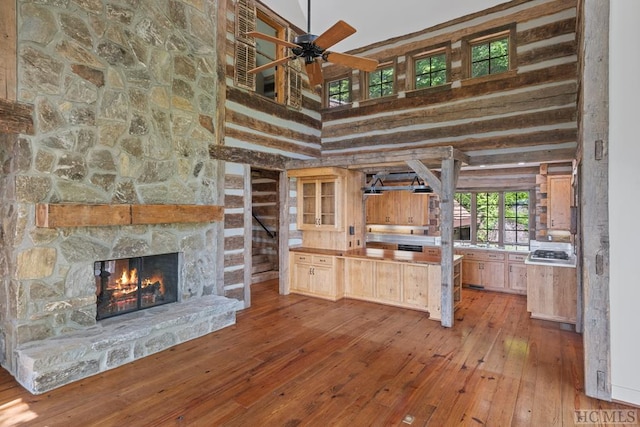 interior space with light hardwood / wood-style floors, a high ceiling, ceiling fan, and a fireplace