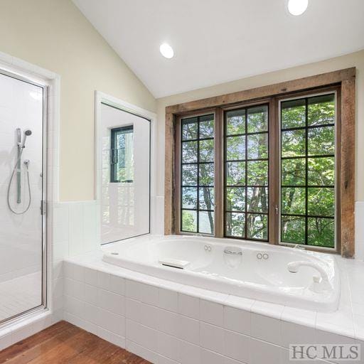 bathroom with vaulted ceiling, a wealth of natural light, shower with separate bathtub, and hardwood / wood-style flooring