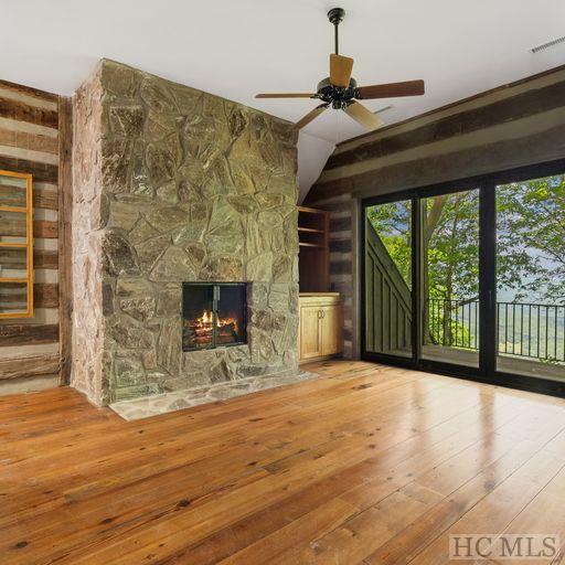 unfurnished living room featuring ceiling fan, wood-type flooring, and a fireplace