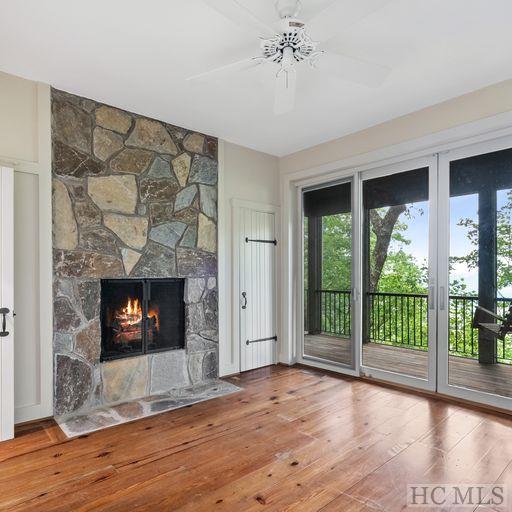 unfurnished living room featuring ceiling fan, wood-type flooring, and a fireplace