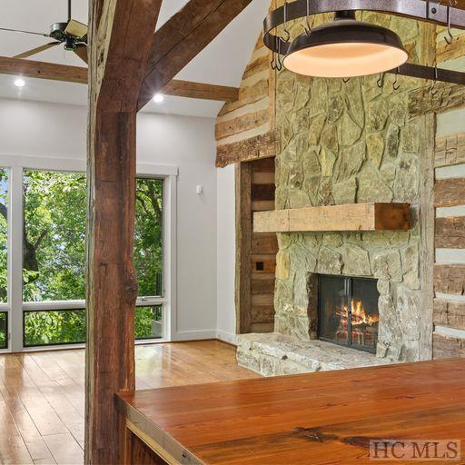 unfurnished living room featuring light wood-type flooring, ceiling fan, a fireplace, and lofted ceiling