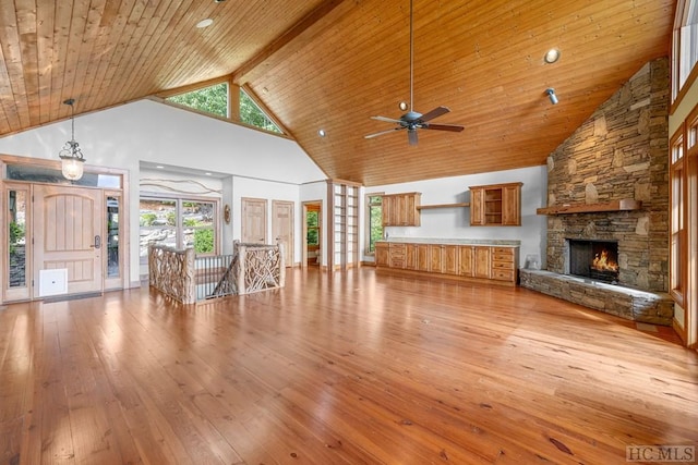 unfurnished living room with a fireplace, high vaulted ceiling, beamed ceiling, wood ceiling, and light hardwood / wood-style flooring