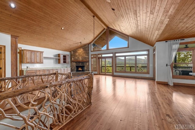 unfurnished living room featuring high vaulted ceiling, light hardwood / wood-style floors, a stone fireplace, wooden ceiling, and beamed ceiling