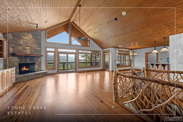 unfurnished living room with wood ceiling, hardwood / wood-style floors, high vaulted ceiling, a fireplace, and ceiling fan with notable chandelier