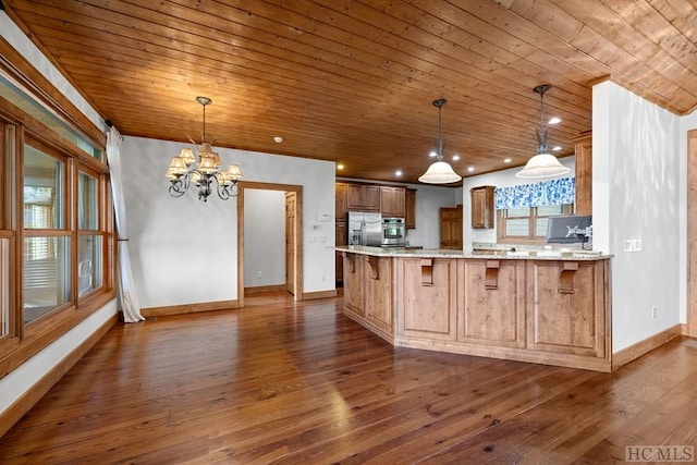 kitchen featuring a kitchen bar, decorative light fixtures, kitchen peninsula, and appliances with stainless steel finishes