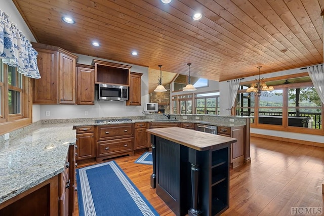 kitchen featuring wood counters, sink, a center island, hanging light fixtures, and stainless steel appliances