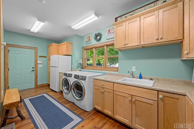 clothes washing area featuring sink, cabinets, independent washer and dryer, and light wood-type flooring