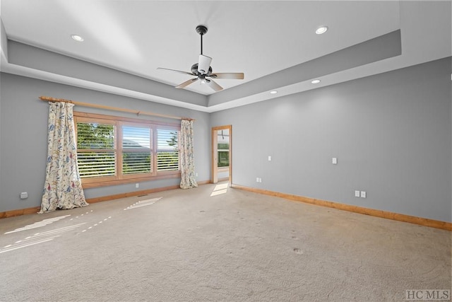 carpeted empty room featuring a raised ceiling and ceiling fan