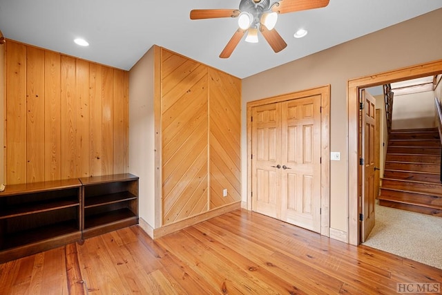 bedroom with light hardwood / wood-style flooring, wooden walls, and ceiling fan