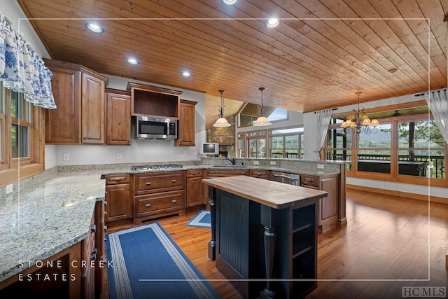 kitchen with pendant lighting, appliances with stainless steel finishes, a kitchen island, wood counters, and wooden ceiling