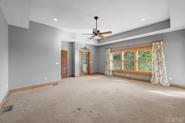 carpeted spare room featuring a raised ceiling and ceiling fan