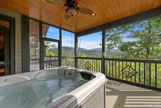 sunroom featuring wooden ceiling, a jacuzzi, and a mountain view