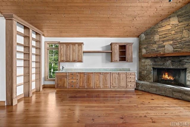 kitchen with vaulted ceiling, a fireplace, sink, wood ceiling, and light hardwood / wood-style floors