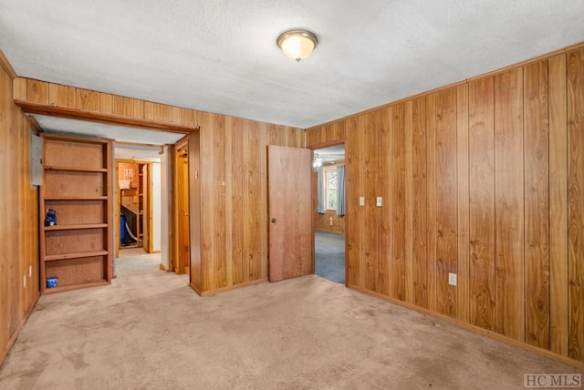 empty room with carpet flooring, wooden walls, and a textured ceiling