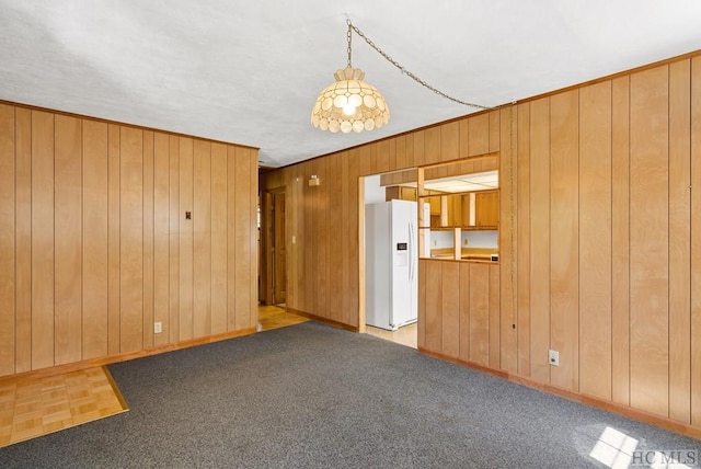 spare room featuring ornamental molding, light carpet, and wooden walls