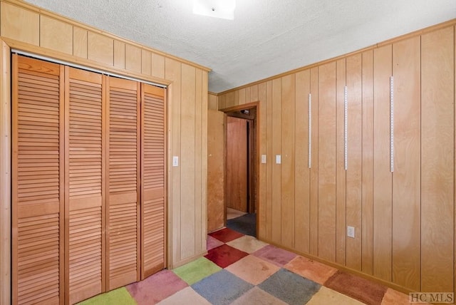 unfurnished bedroom with a closet, wood walls, and a textured ceiling