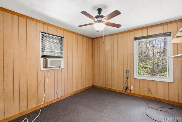 carpeted spare room with ceiling fan, cooling unit, and wood walls