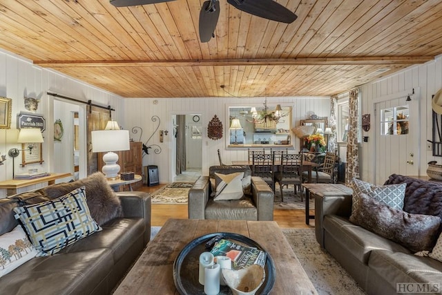 living room with a barn door, wood walls, hardwood / wood-style floors, wood ceiling, and ceiling fan with notable chandelier