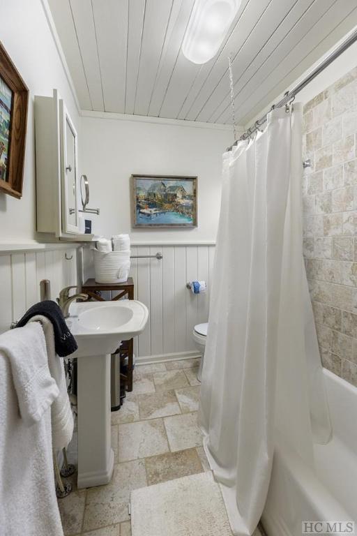 bathroom with wooden ceiling, toilet, crown molding, and shower / tub combo