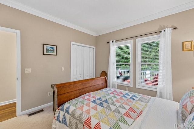 bedroom featuring light carpet, crown molding, and a closet