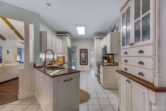 kitchen with appliances with stainless steel finishes, kitchen peninsula, sink, and light tile patterned floors