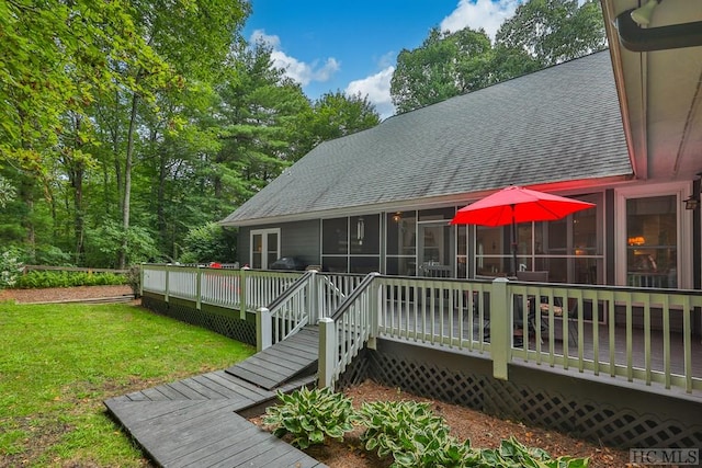 rear view of property featuring a wooden deck, a yard, and a sunroom