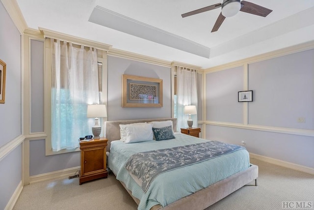 bedroom with crown molding, ceiling fan, a tray ceiling, and light colored carpet