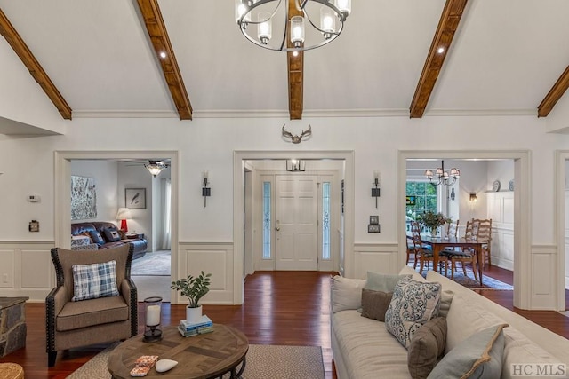 living room with ceiling fan with notable chandelier, dark hardwood / wood-style flooring, and lofted ceiling with beams