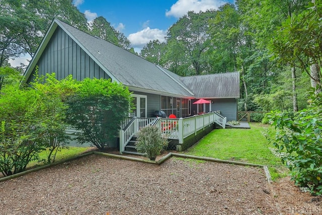 back of property with a wooden deck and a lawn